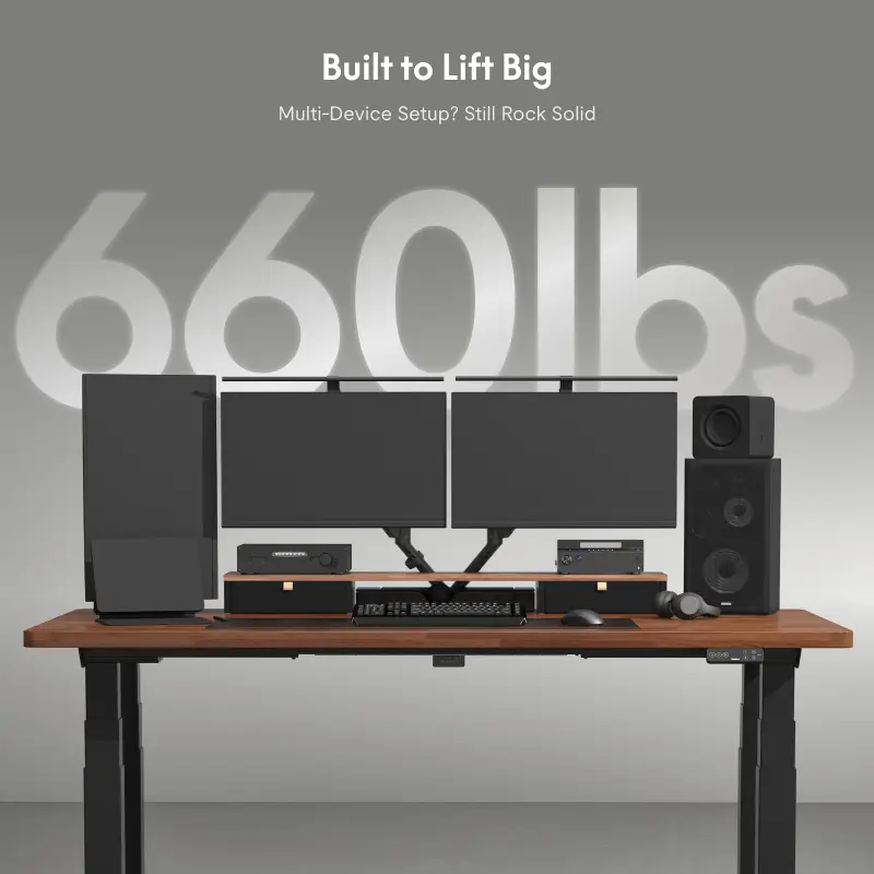 Dual monitors and speakers on an adjustable standing desk in a modern office setting