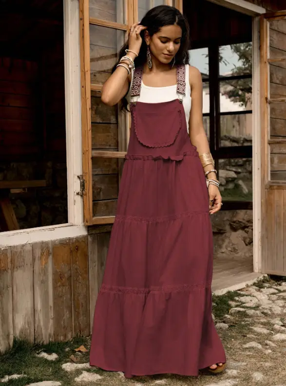Woman in a long burgundy dress standing by a rustic wooden cabin doorway