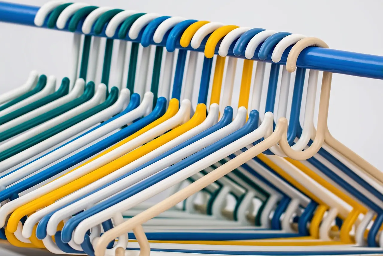Colorful plastic hangers on a blue rod in a close-up arrangement