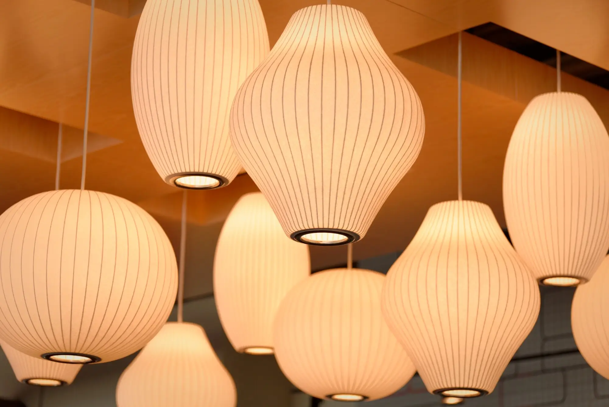 Modern pendant lights with ribbed textures hanging from wooden ceiling in warm lighting ambiance