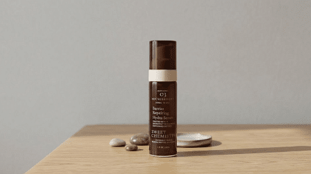Sweet Chemistry Barrier Repairing Hydra Serum bottle placed on a wooden surface with minimal background setup