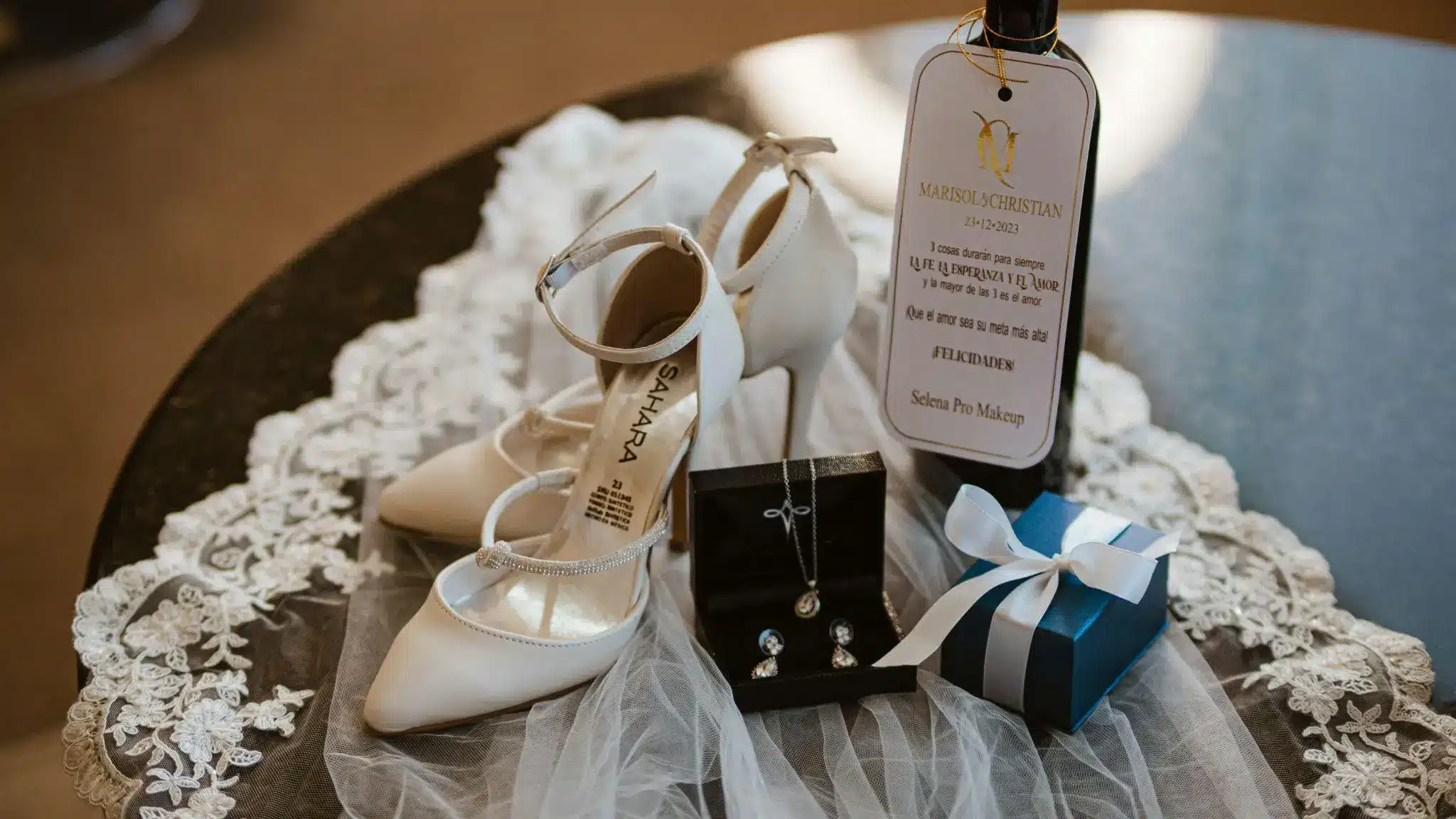 White bridal shoes and jewelry on lace fabric with gift box on black table