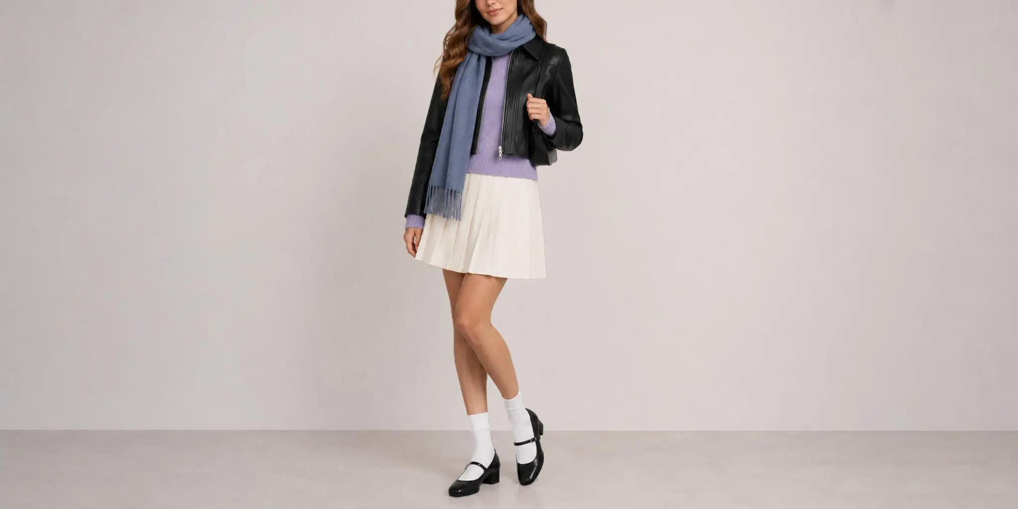 Woman in black jacket and blue scarf with white pleated skirt in minimalist indoor setting