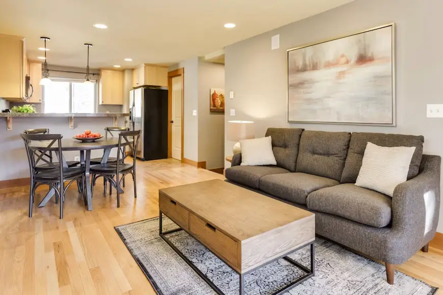 Contemporary living room with gray sofa, wooden coffee table, and dining area in open concept space
