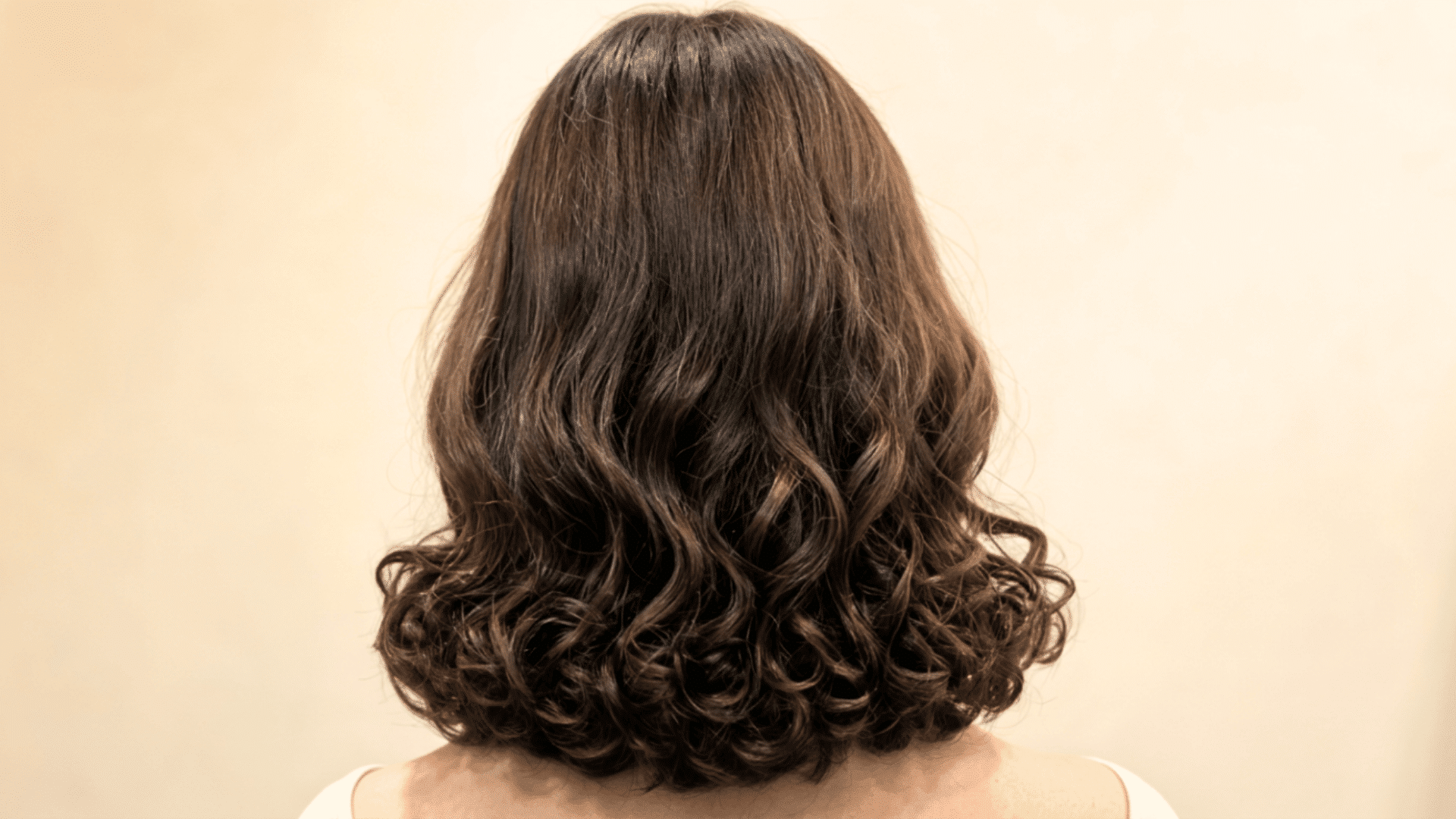 Woman with a shoulder-length lob that defines loose upper waves and balances curlier lower sections.
