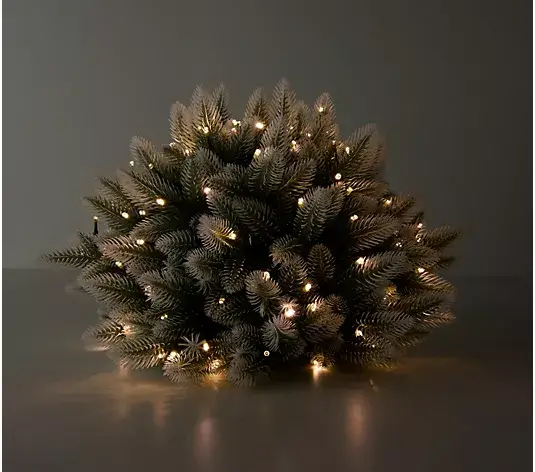 Artificial Christmas tree with warm white lights in a dimly lit room