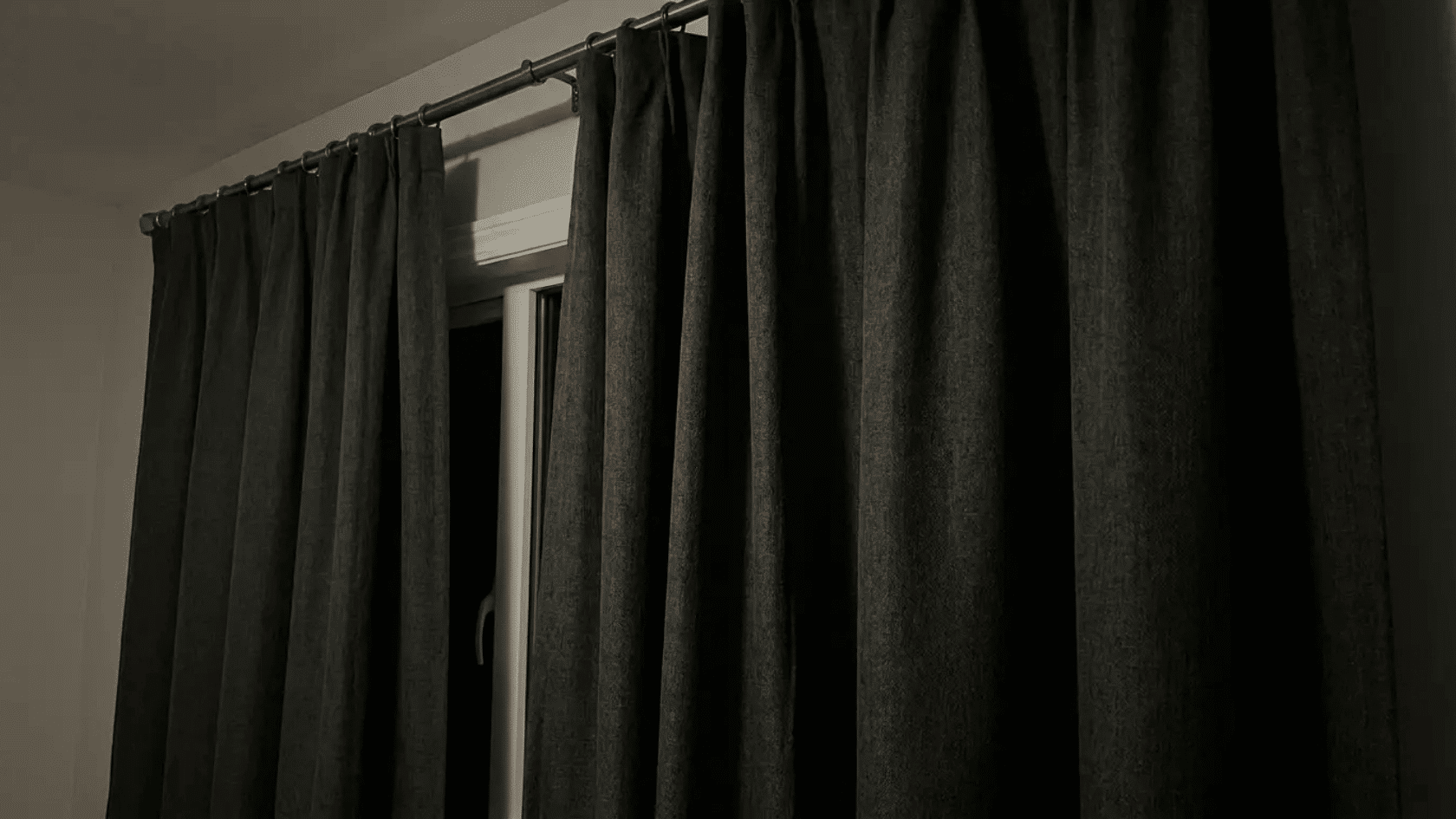 Black blockout curtains covering a window to create a dark, private room environment.