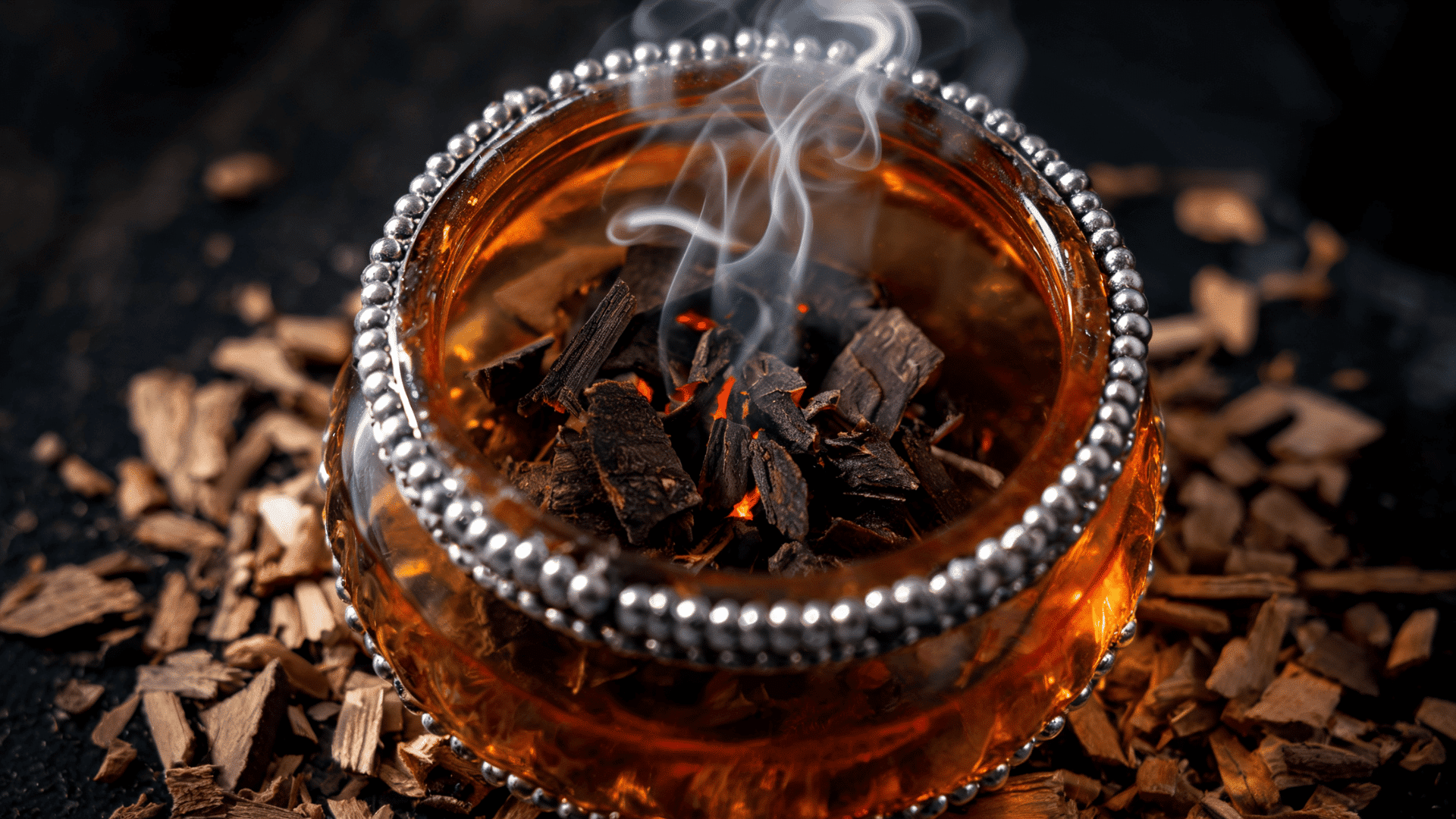 Burning oud wood chips releasing smoke in a decorative incense burner
