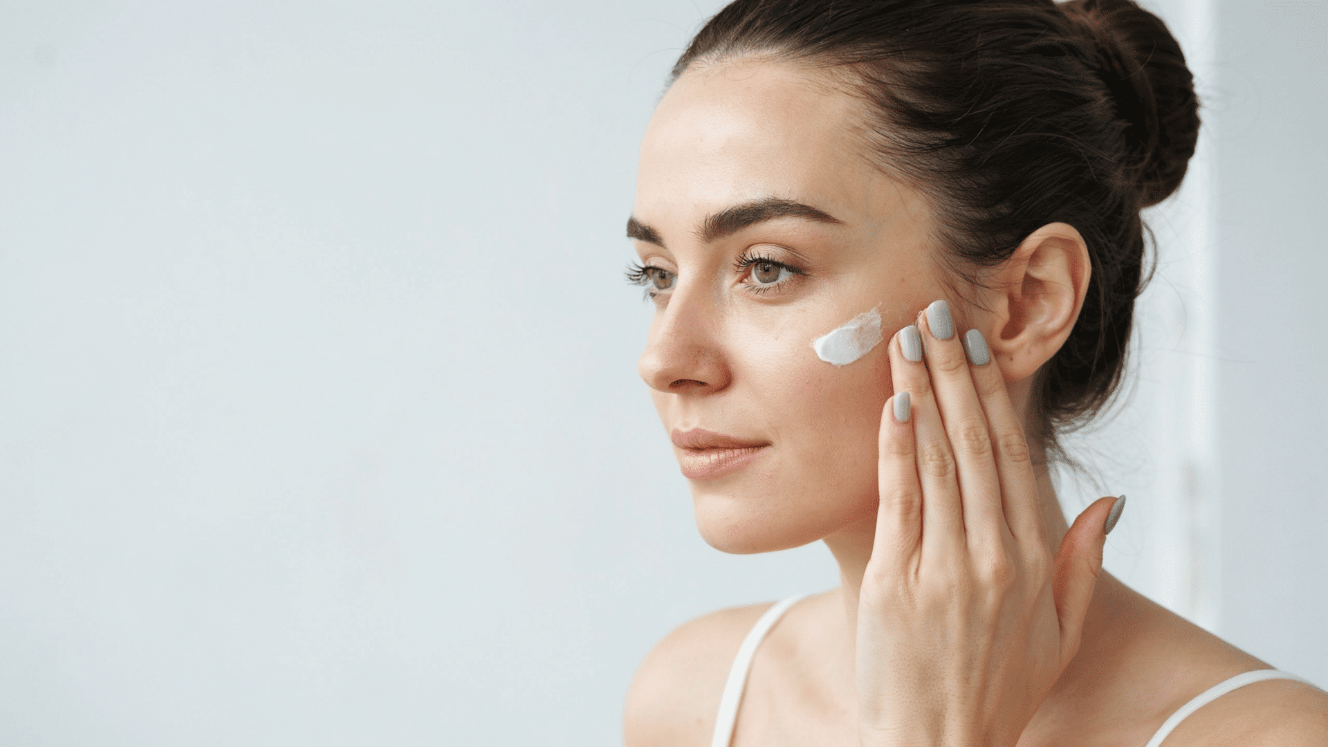 Woman applying moisturizer for a natural face skin care routine at home for firmer-looking skin