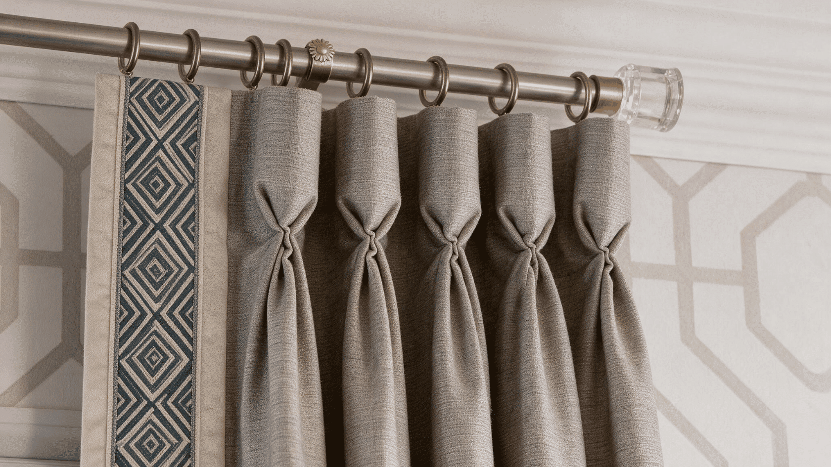 Gray pinch pleat curtains with tailored folds hanging from a decorative curtain rod.