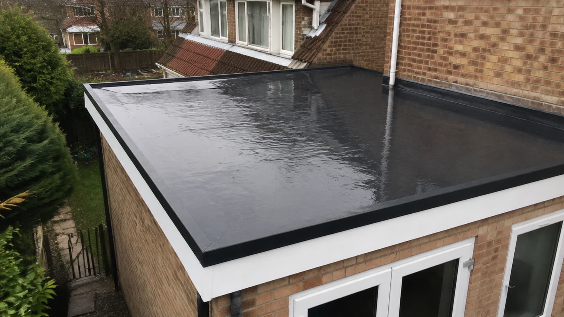 high angle view of a suburban house with flat black rubber epdm roof membrane and wet surface finish