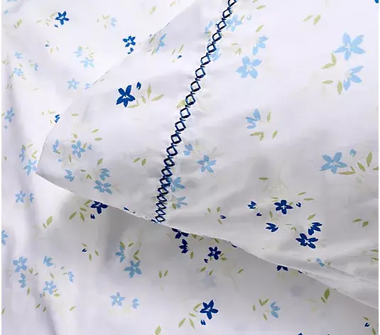 White pillow and bedsheet with blue floral pattern and decorative stitching