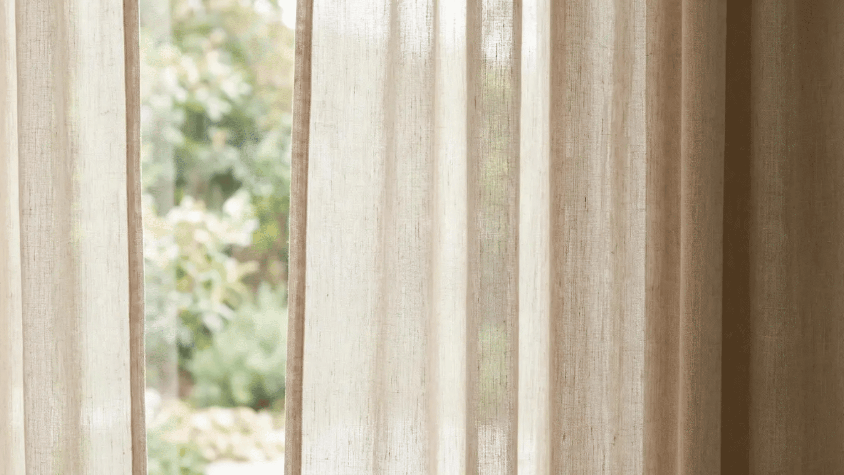 Light-filtering linen curtains softly diffusing sunlight through a window in a cozy room.