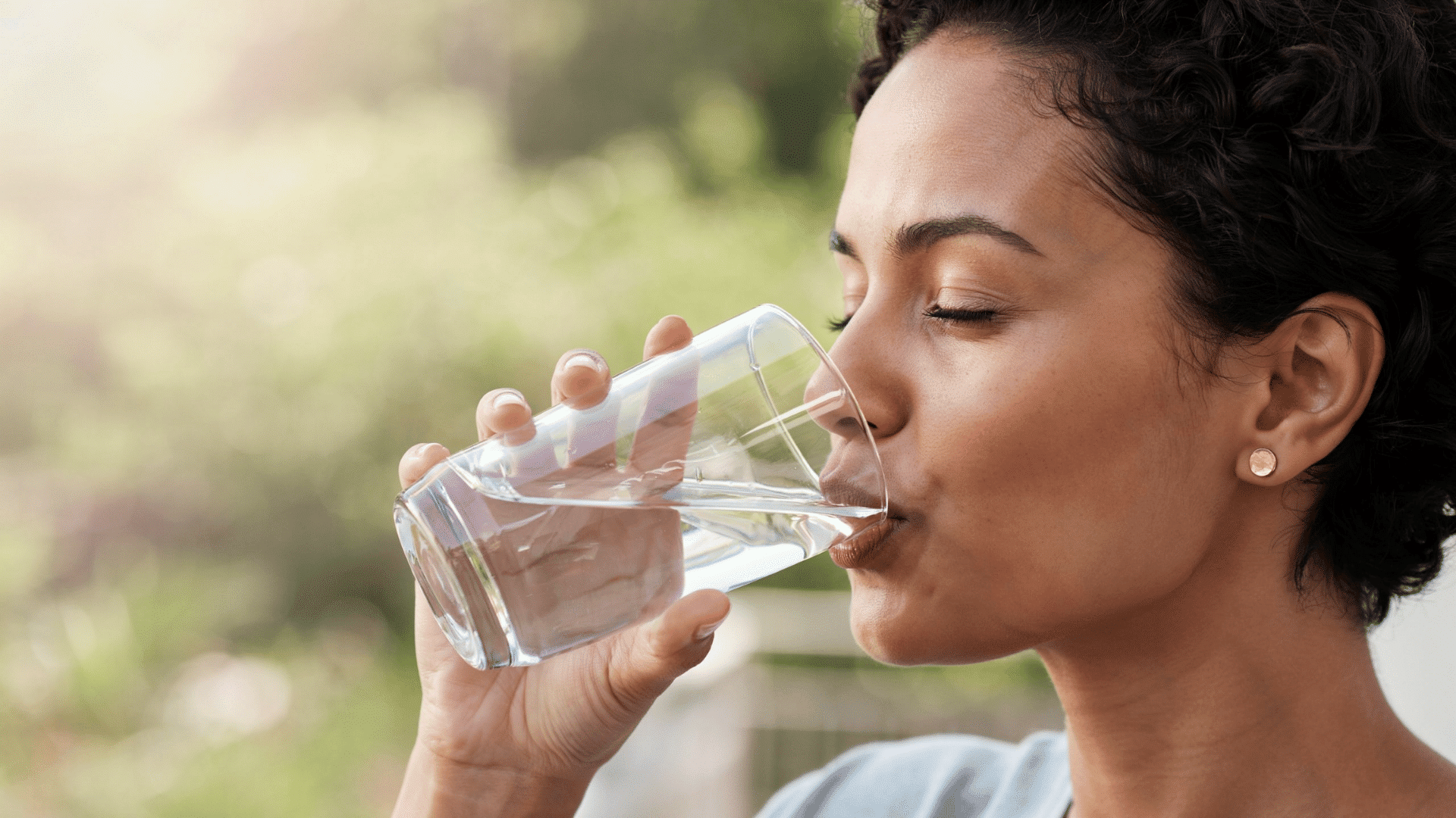 Woman drinking water to support hydration for a natural face skin care routine at home