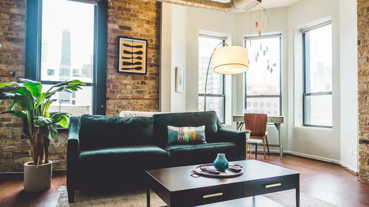 Cozy living room with dark green sofa and modern decor in a brick-walled apartment