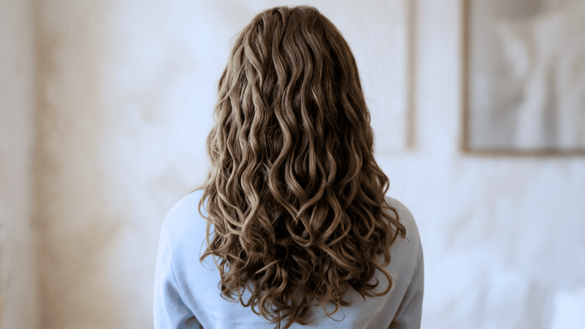 Woman with long layers that balance loose upper waves and fuller curls underneath.