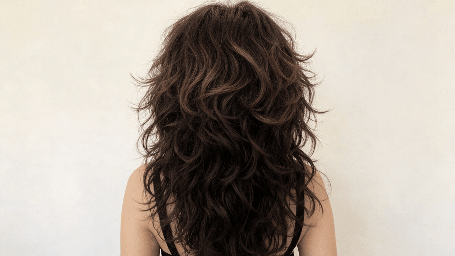 Woman with a shag-style layered cut showing softer crown movement and curlier sections underneath.