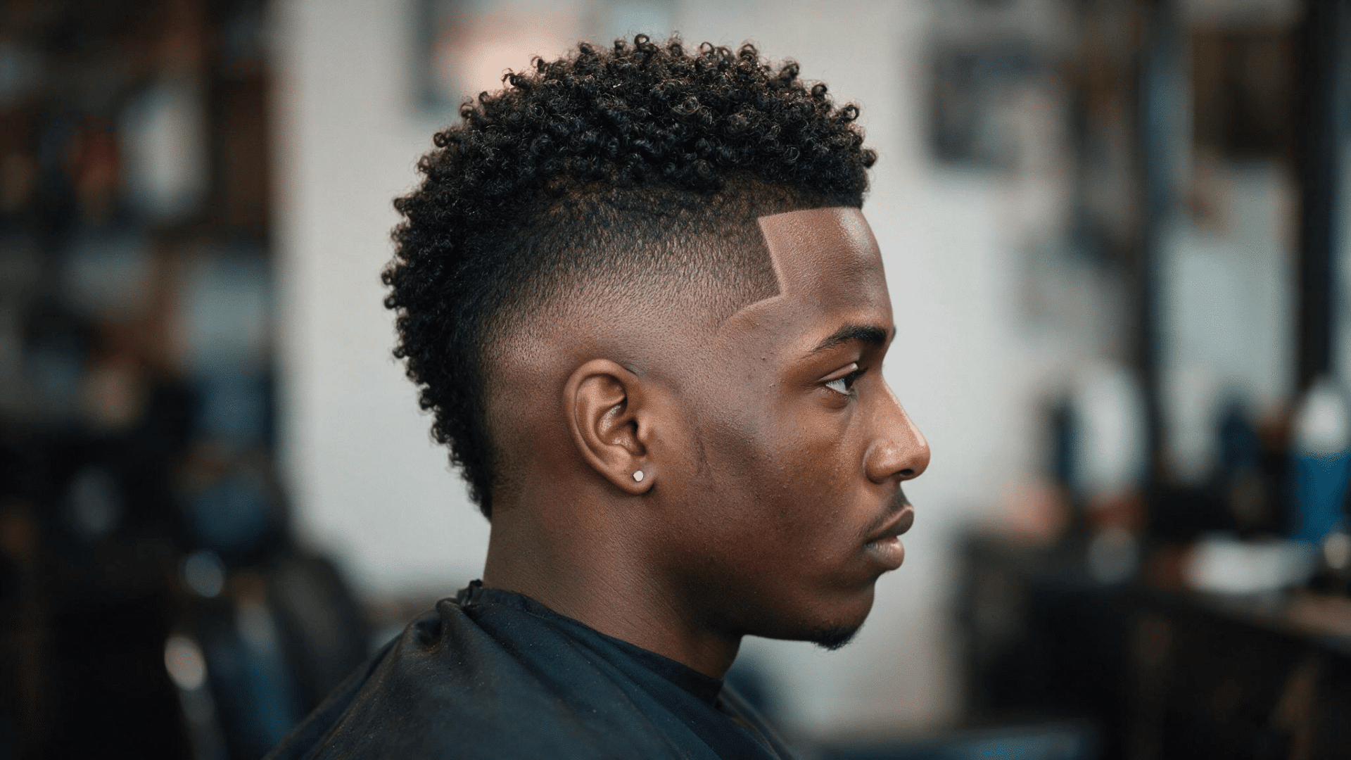 afro mohawk with dense natural curls through the center and closely faded sides