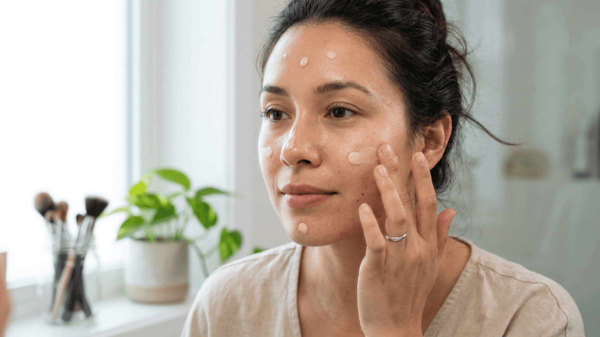 woman applying BB cream dots to her face with fingertips for an even and natural finish.