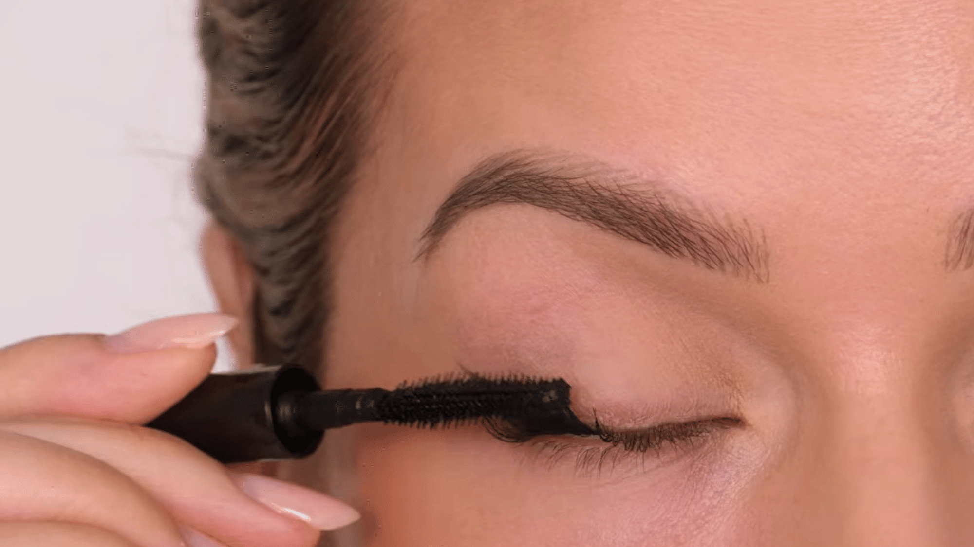 applying mascara with more focus on the outer lashes to add lift length and definition for a winged eye look