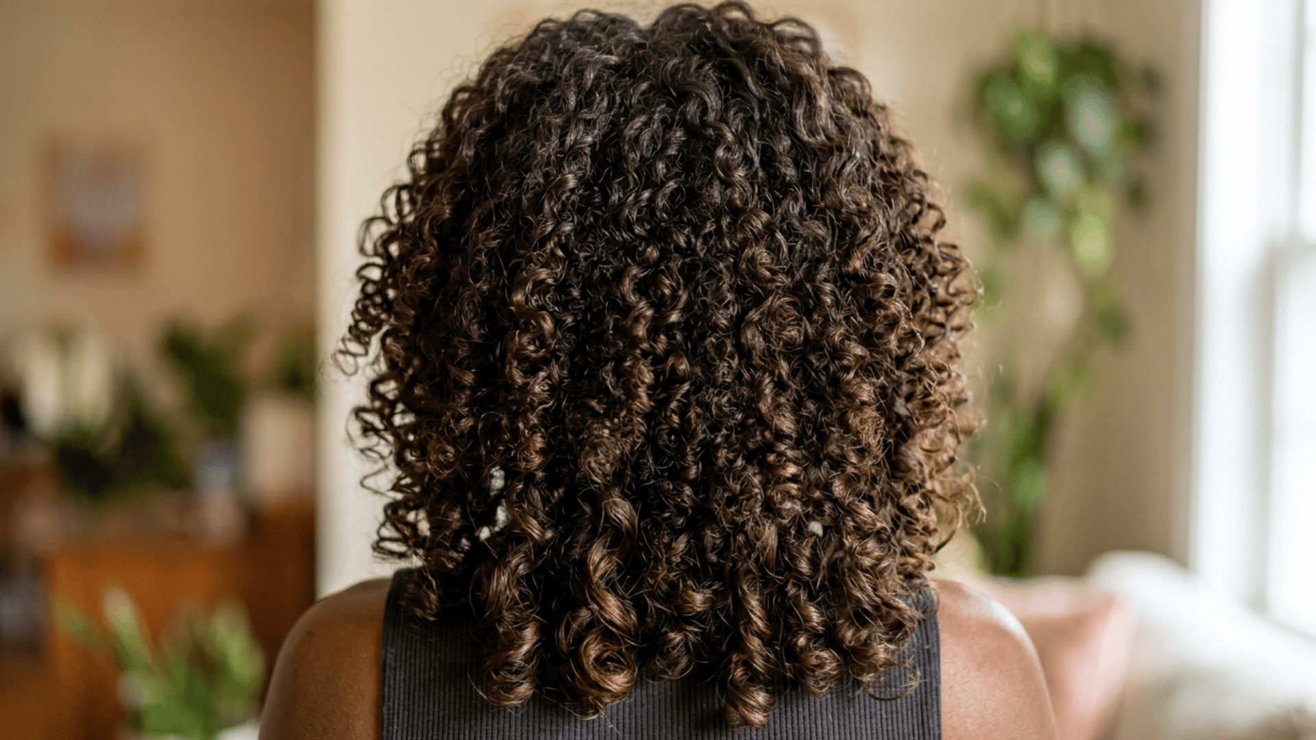 Back view of a person with defined, dark brown curly hair