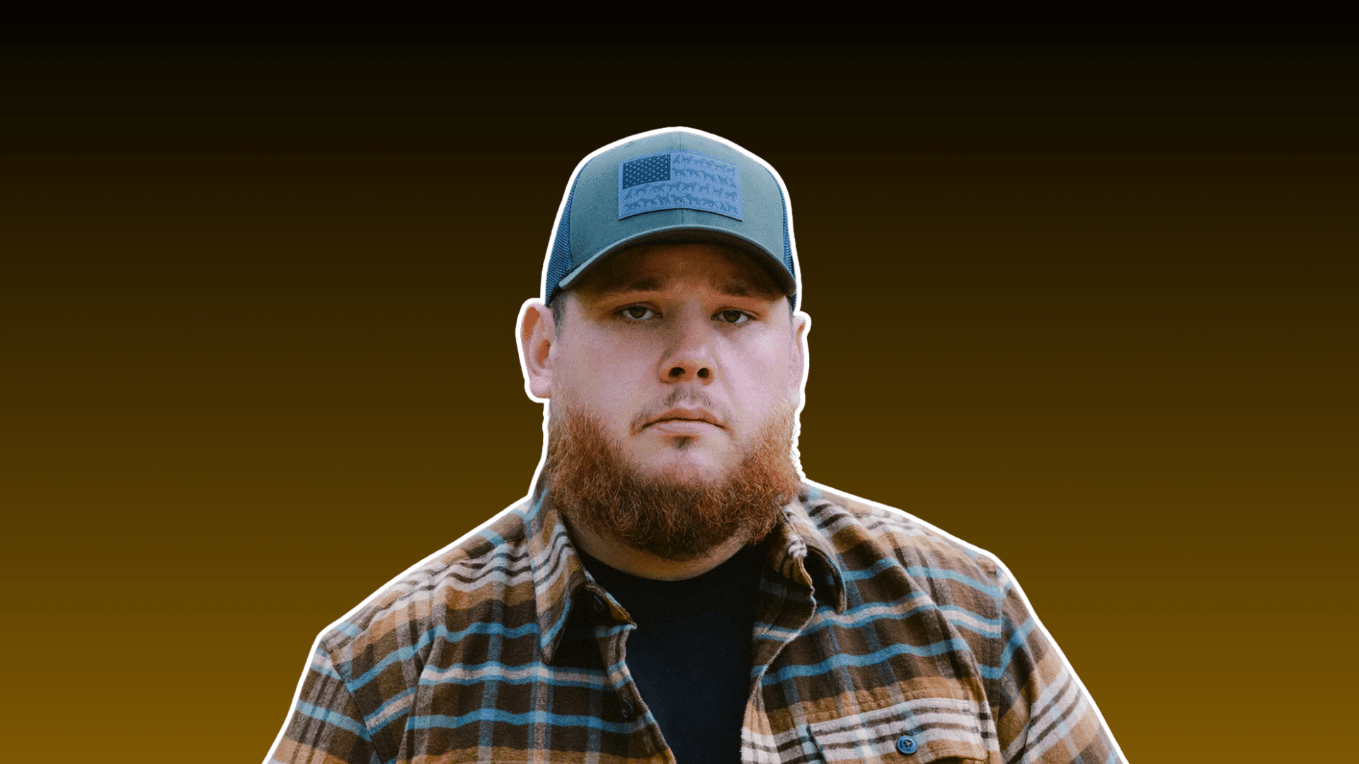 bearded man wearing a baseball cap and plaid shirt posing against a dark brown background