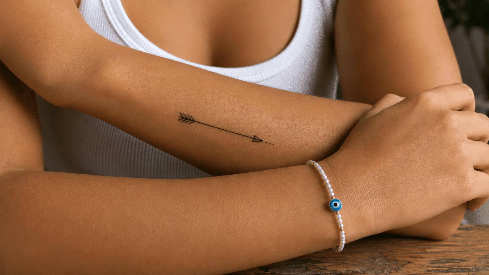 black arrow tattoo with fine-line details and small dots on the inner forearm.
