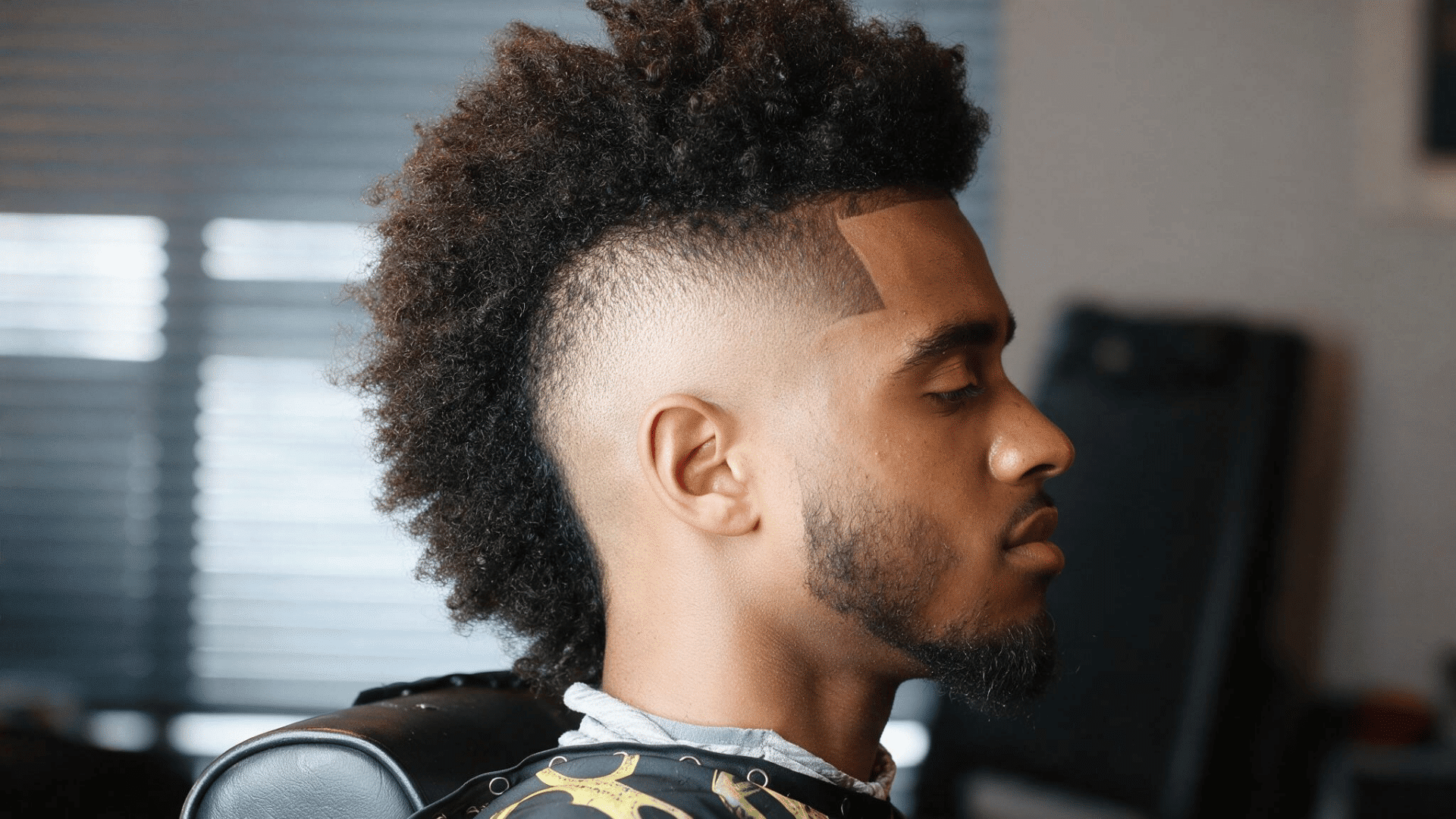 black man with a textured frohawk and mid fade creating a clean contrast along the sides