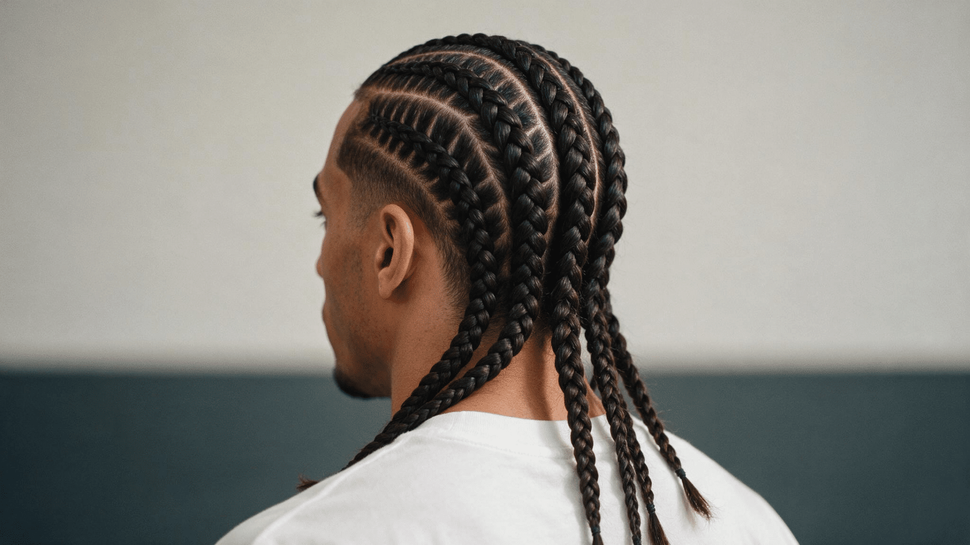 black man with long braided curly hair and mid drop fade