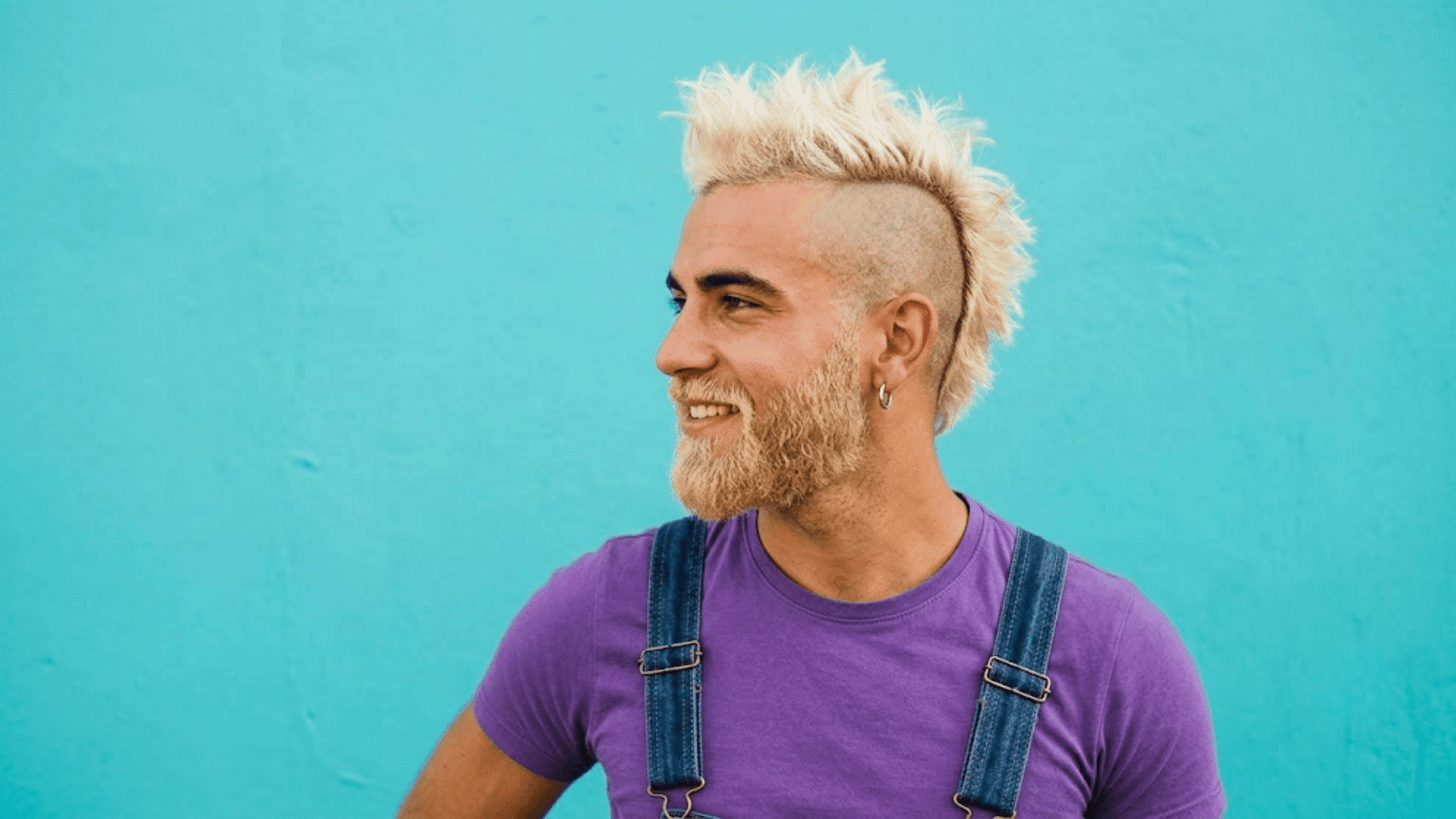 bleached mohawk with platinum textured hair and shaved sides against a blue background