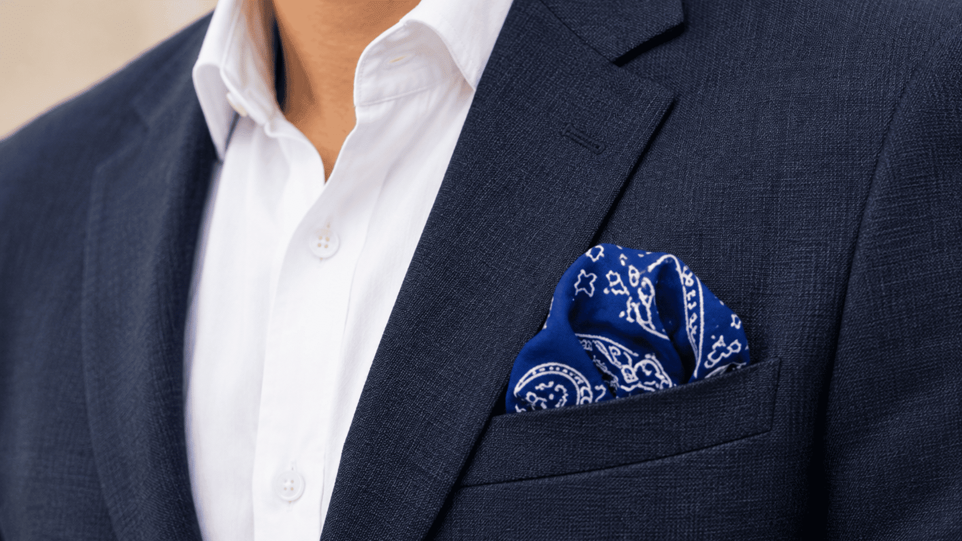blue paisley bandana styled as a puff pocket square in a navy blazer, paired with a crisp white shirt.