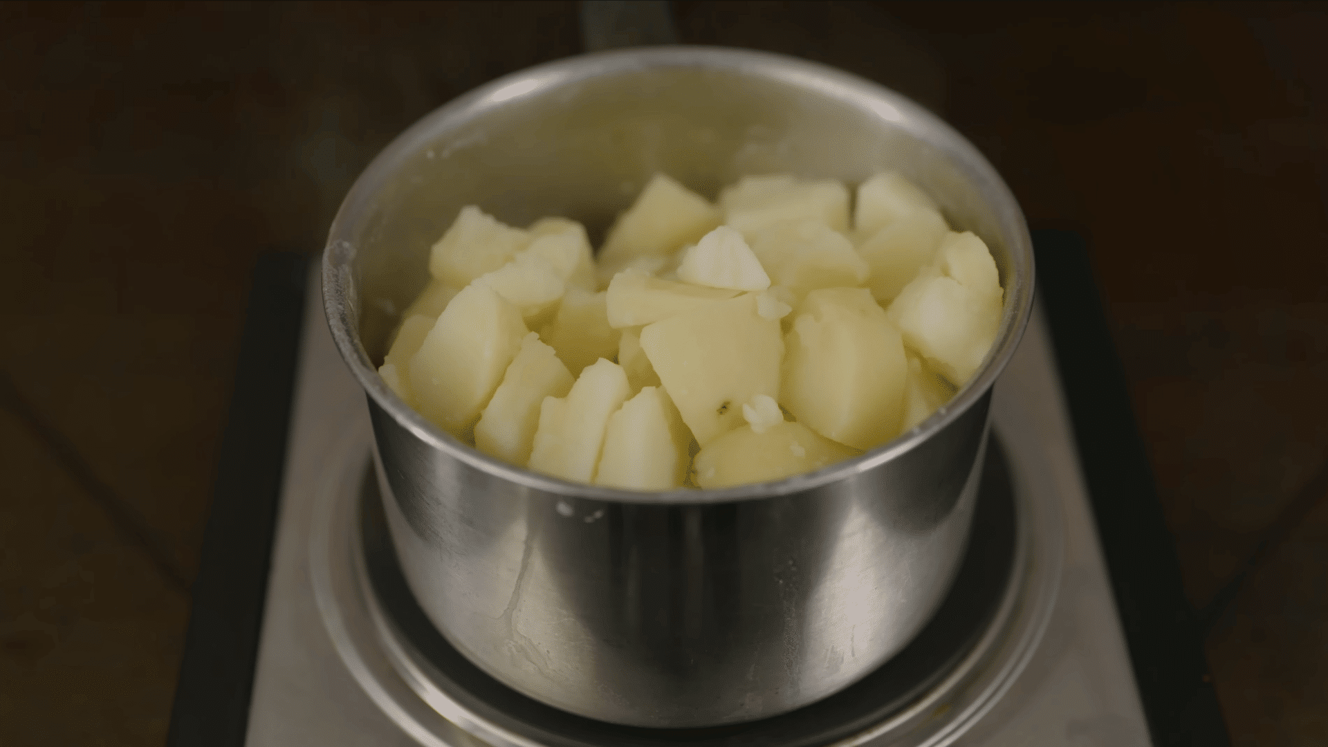 boiled potato chunks resting in a stainless steel pot after draining to remove excess moisture before serving