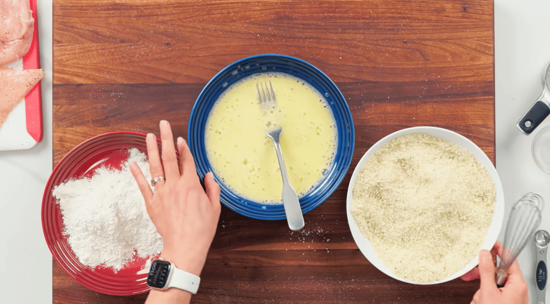 breading station with flour, egg wash, and seasoned panko breadcrumbs ready for coating chicken cutlets.