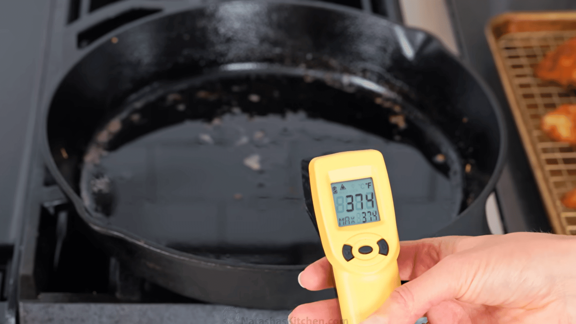 checking frying oil temperature in a cast iron skillet before cooking chicken cutlets.
