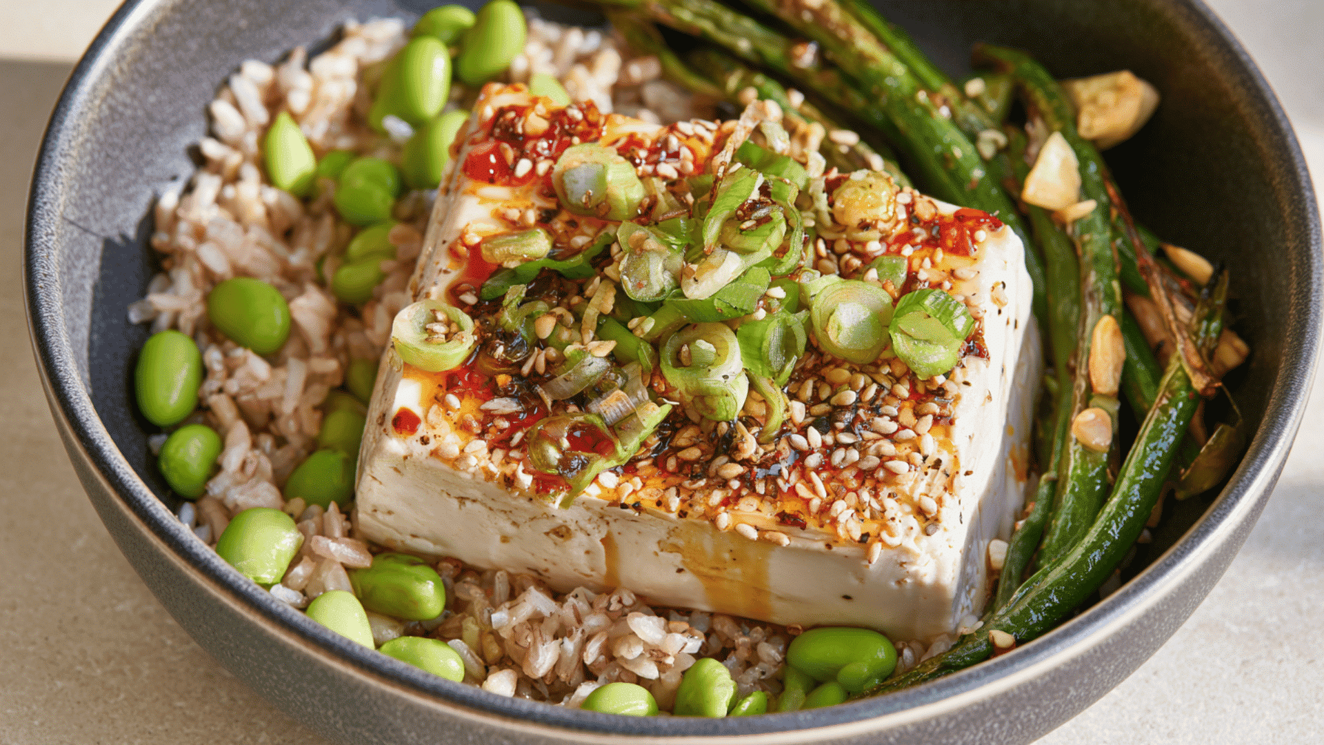 chili garlic silken tofu topped with sesame seeds and green onions served with rice edamame and green beans