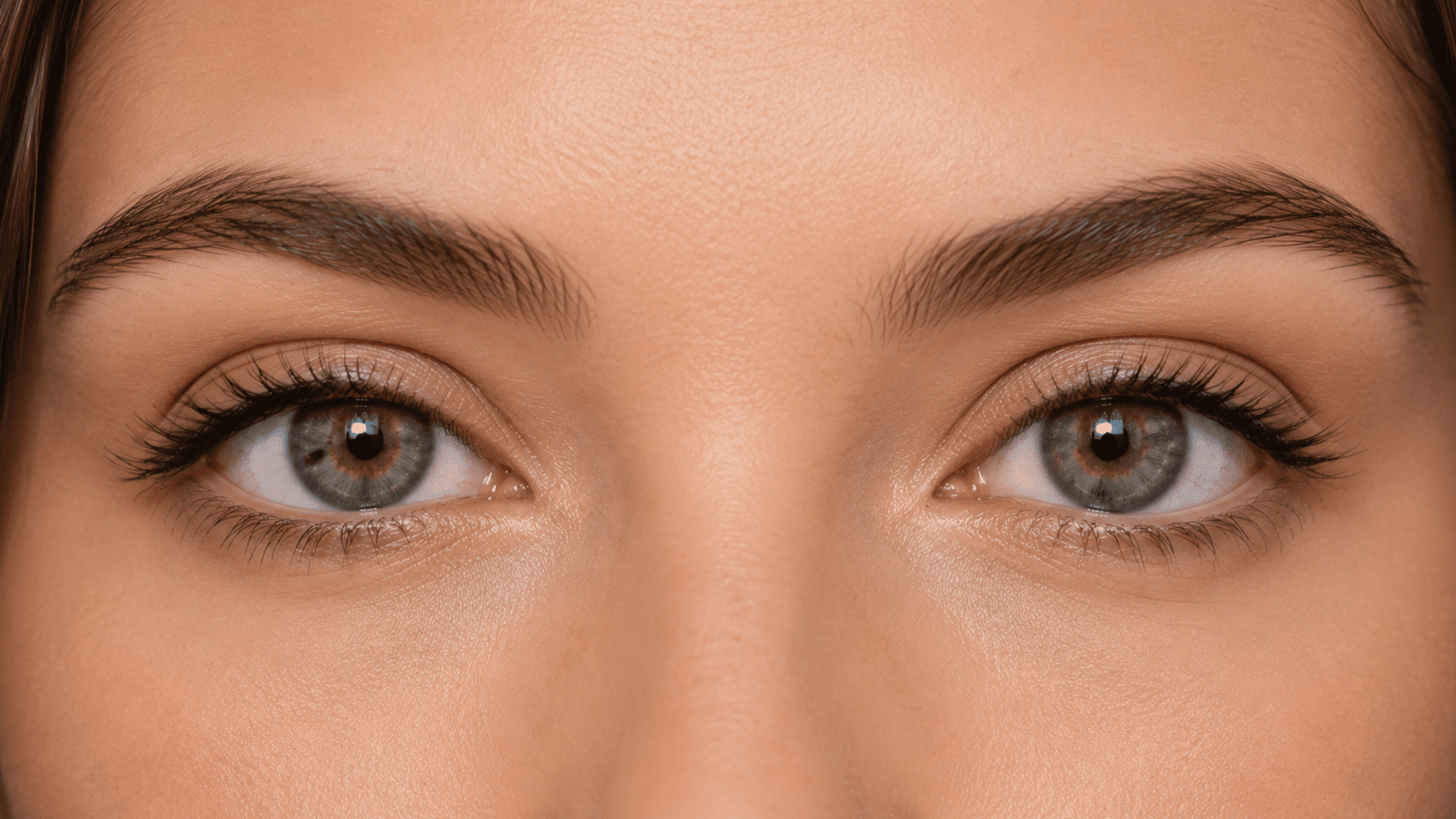 close view of double eyelids with visible upper lid creases light colored eyes defined lashes and natural brows