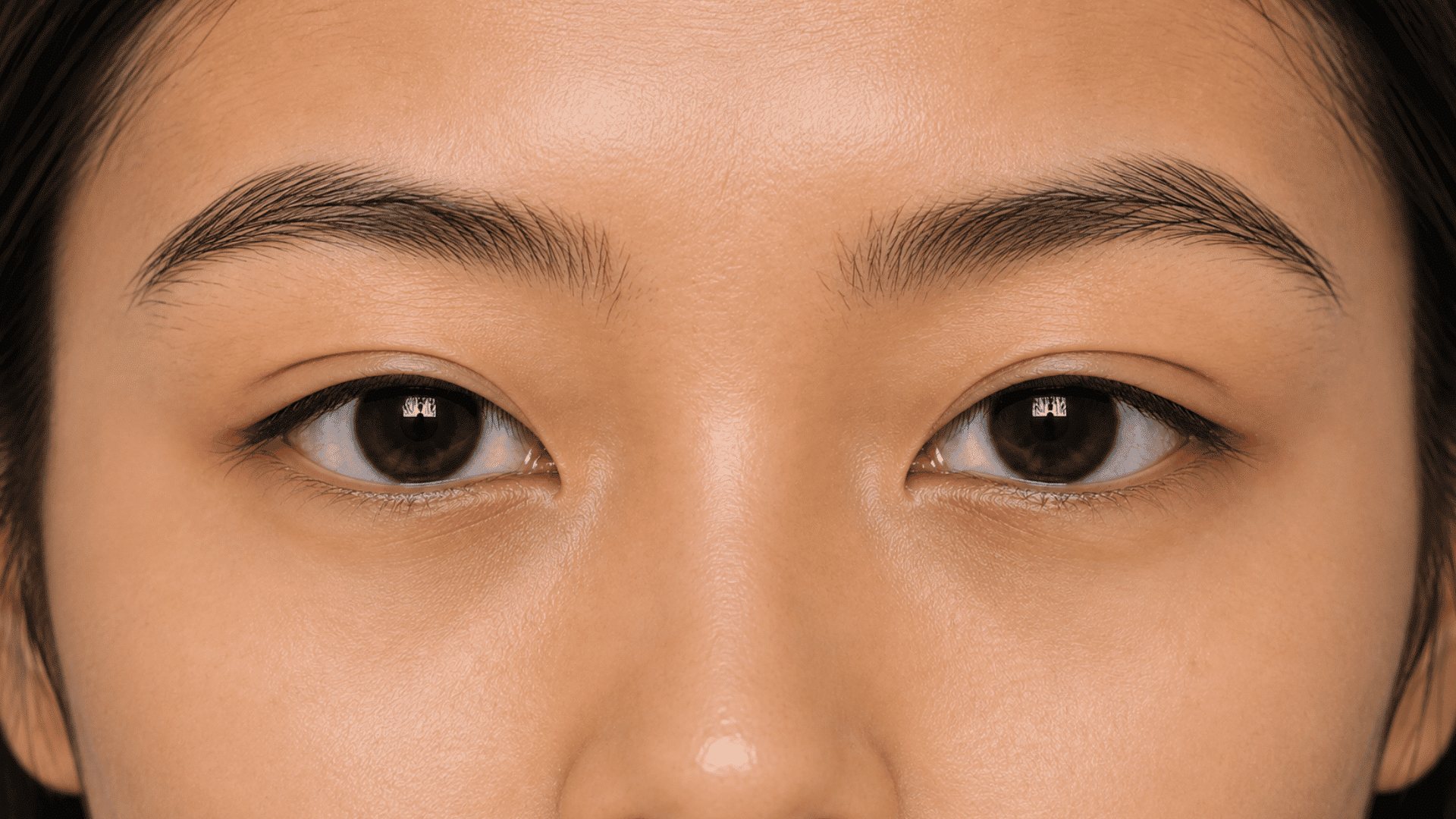 close view of tapered eyelids with brown eyes and natural brows showing a narrow shape toward the outer corners