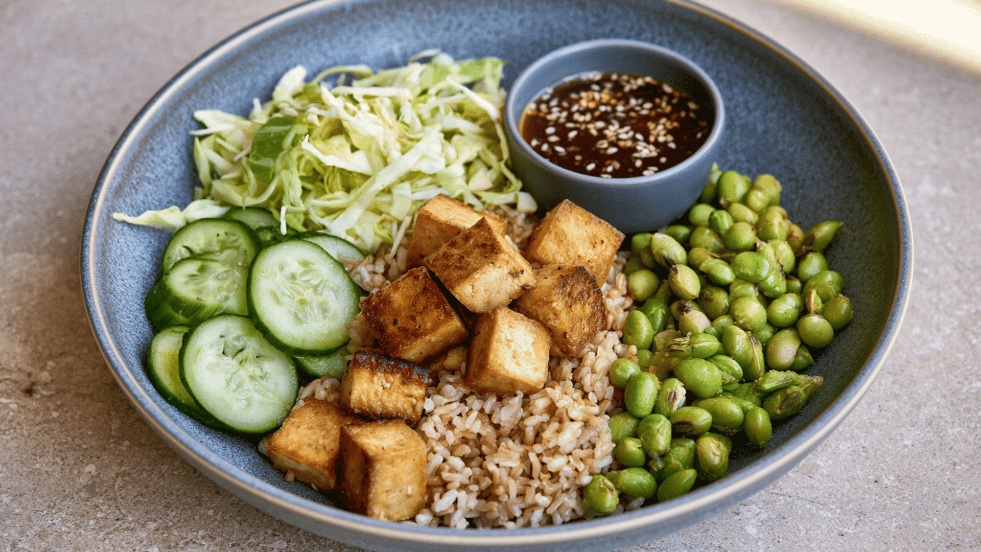 crispy tofu bowl with brown rice edamame cucumber cabbage and sesame soy dressing served on the side