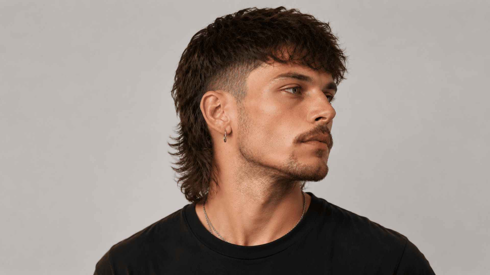 curly mullet haircut with faded sides longer textured back and defined curls creating a bold modern hairstyle for men