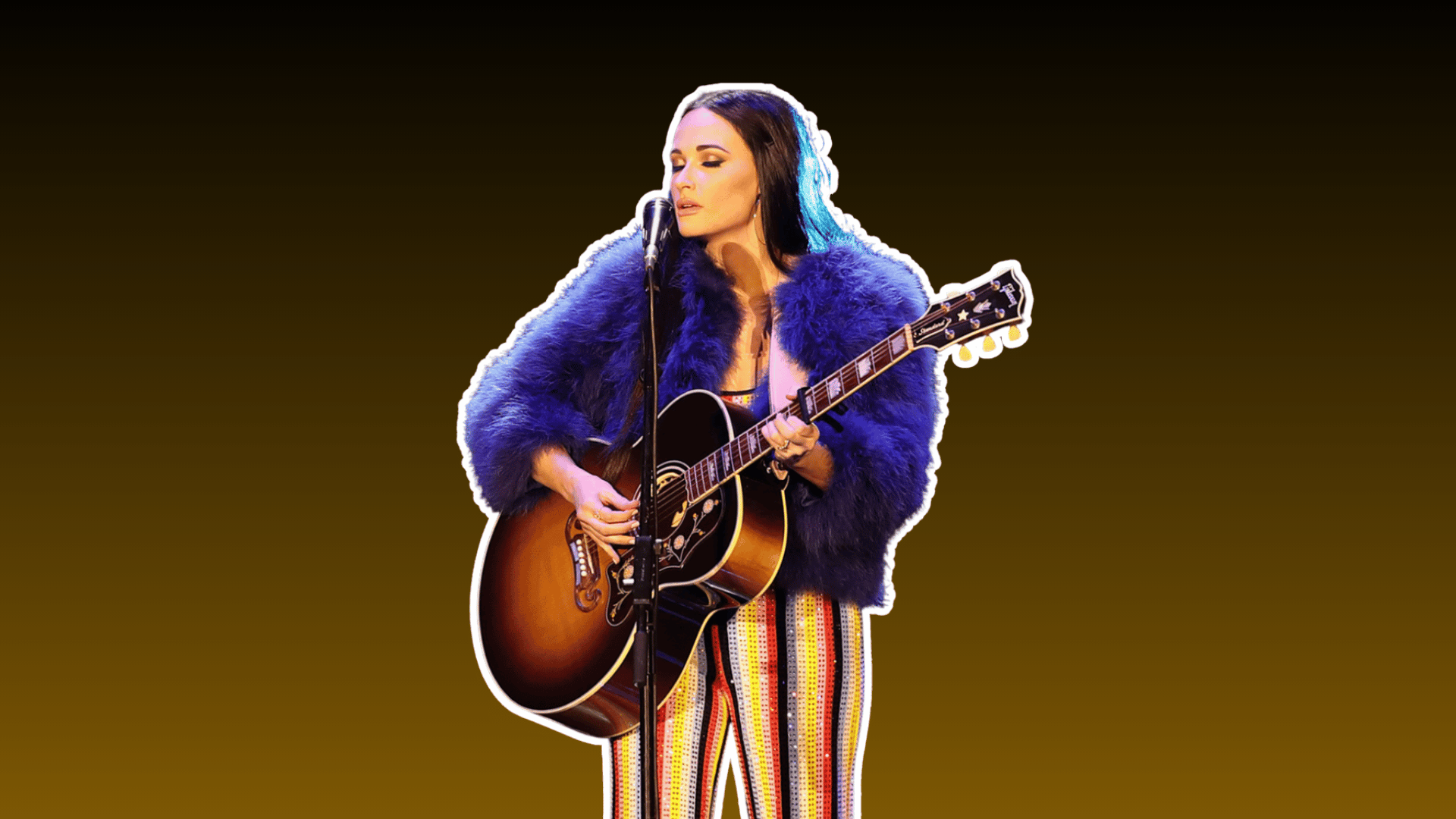female country musician singing into a microphone while playing acoustic guitar in a purple jacket and striped pants