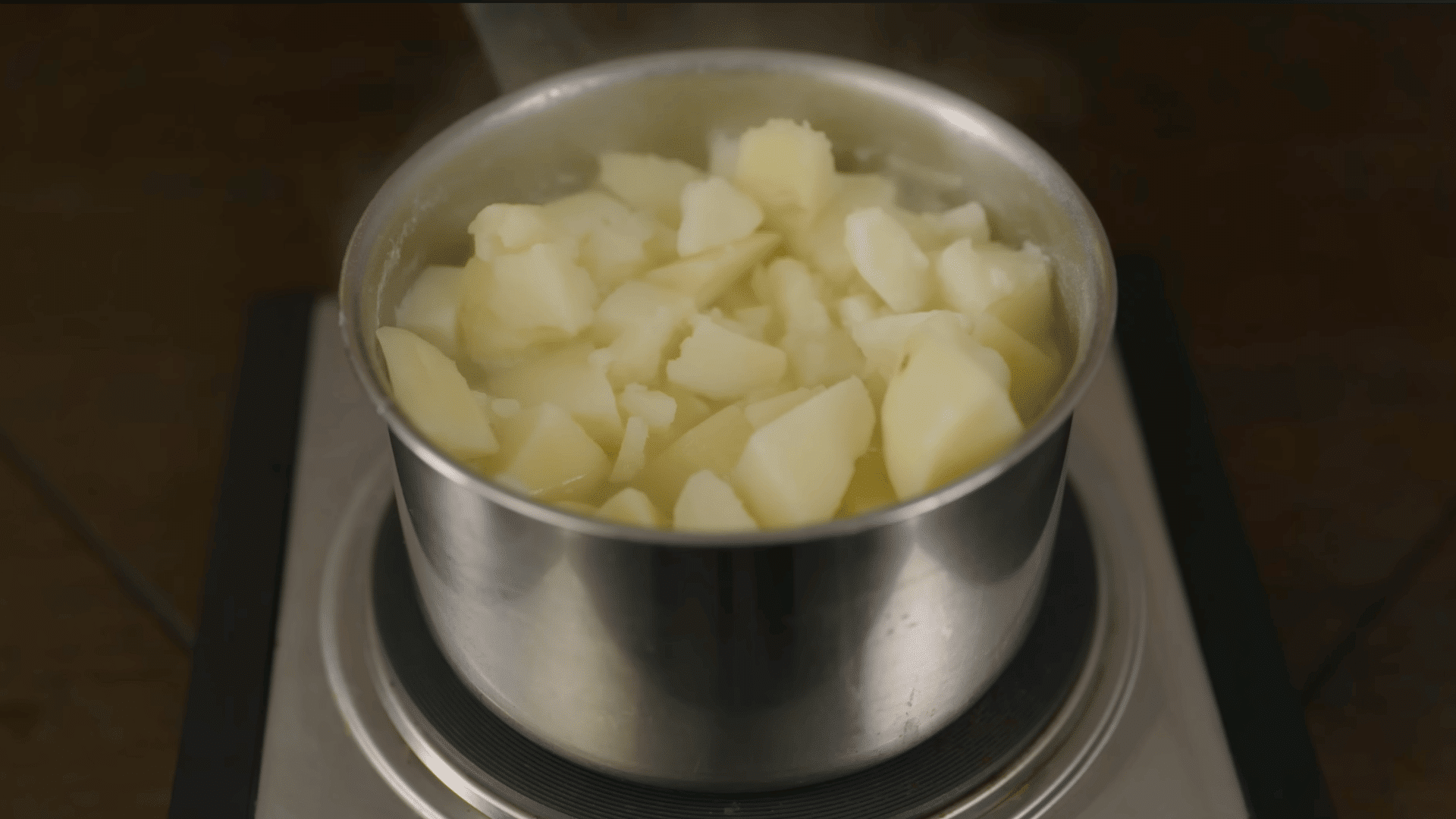 fork checking the center of a boiled potato to test if it is soft and fully cooked