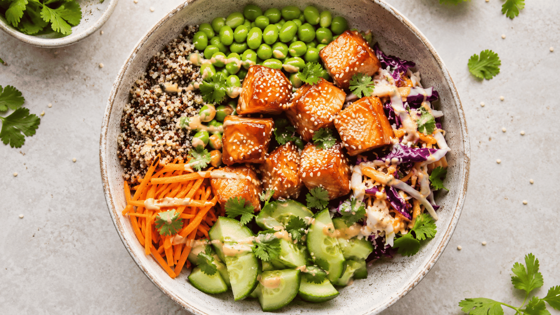 grilled salmon quinoa bowl with cucumber tomatoes olives red onion feta cheese and fresh lemon wedges