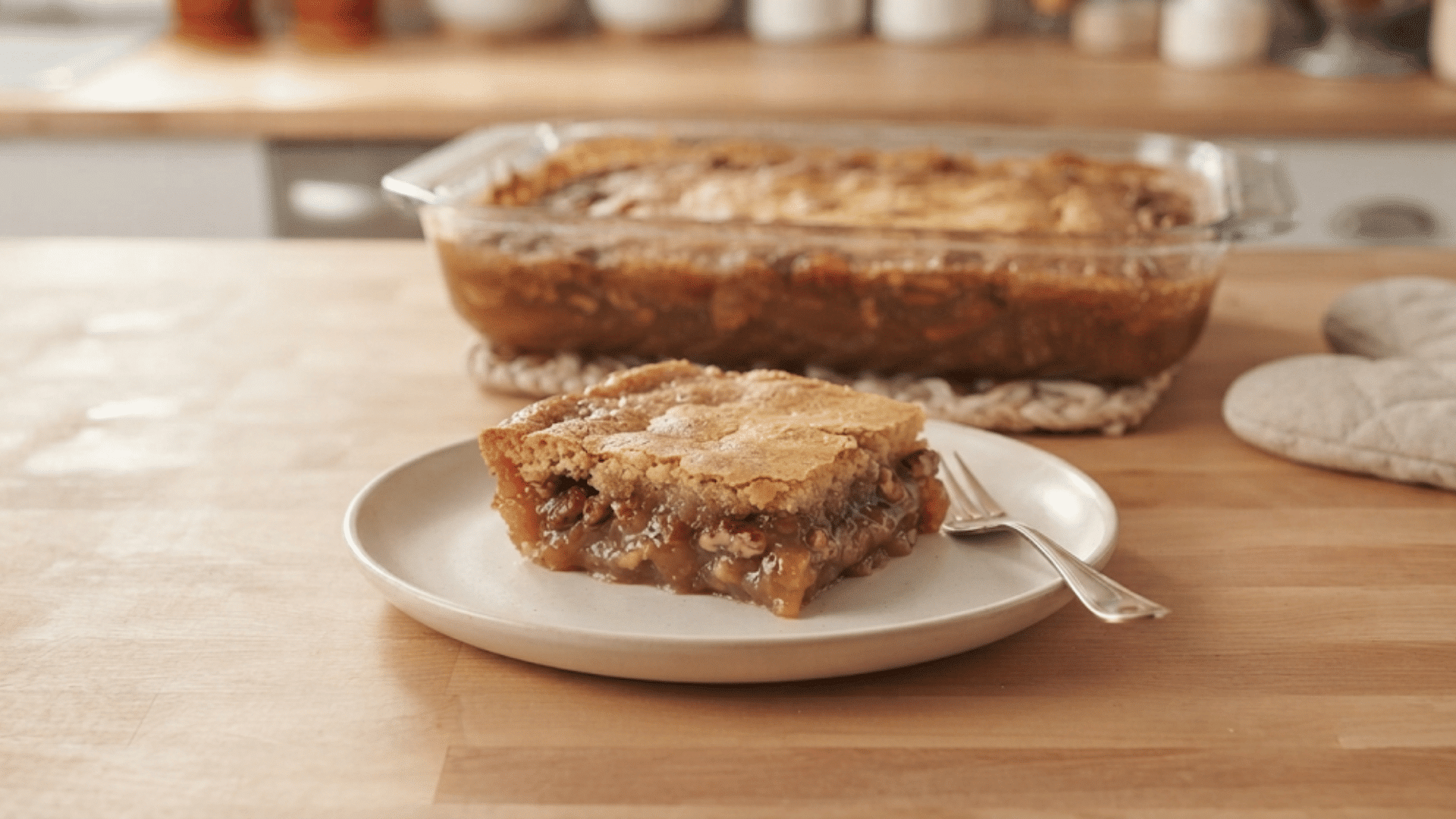 homemade pecan pie bar with a golden crust and rich gooey pecan filling served on a plate beside the baking dish