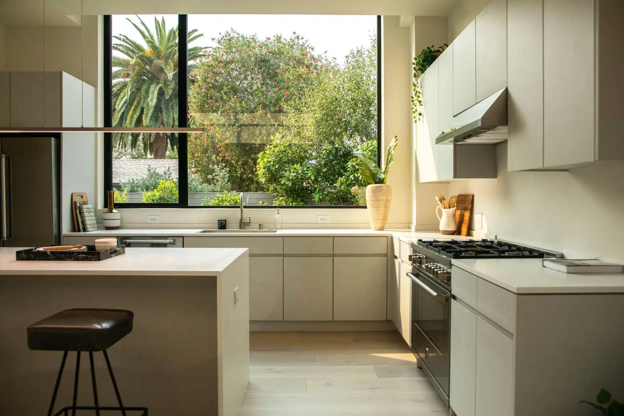 Modern kitchen with large windows, light cabinetry, and stainless steel appliances in natural light
