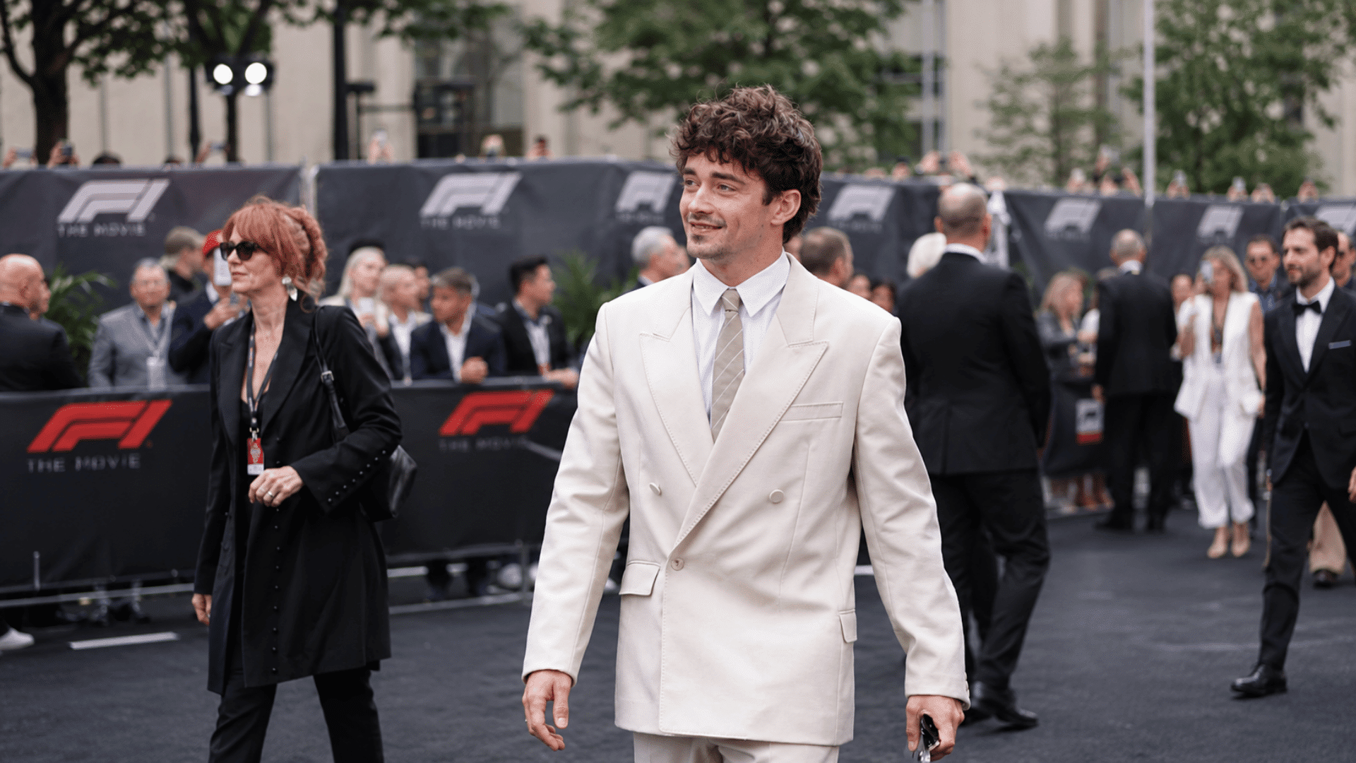 man wearing a curly caesar haircut with cream double breasted suit white shirt and light tie at a formal event