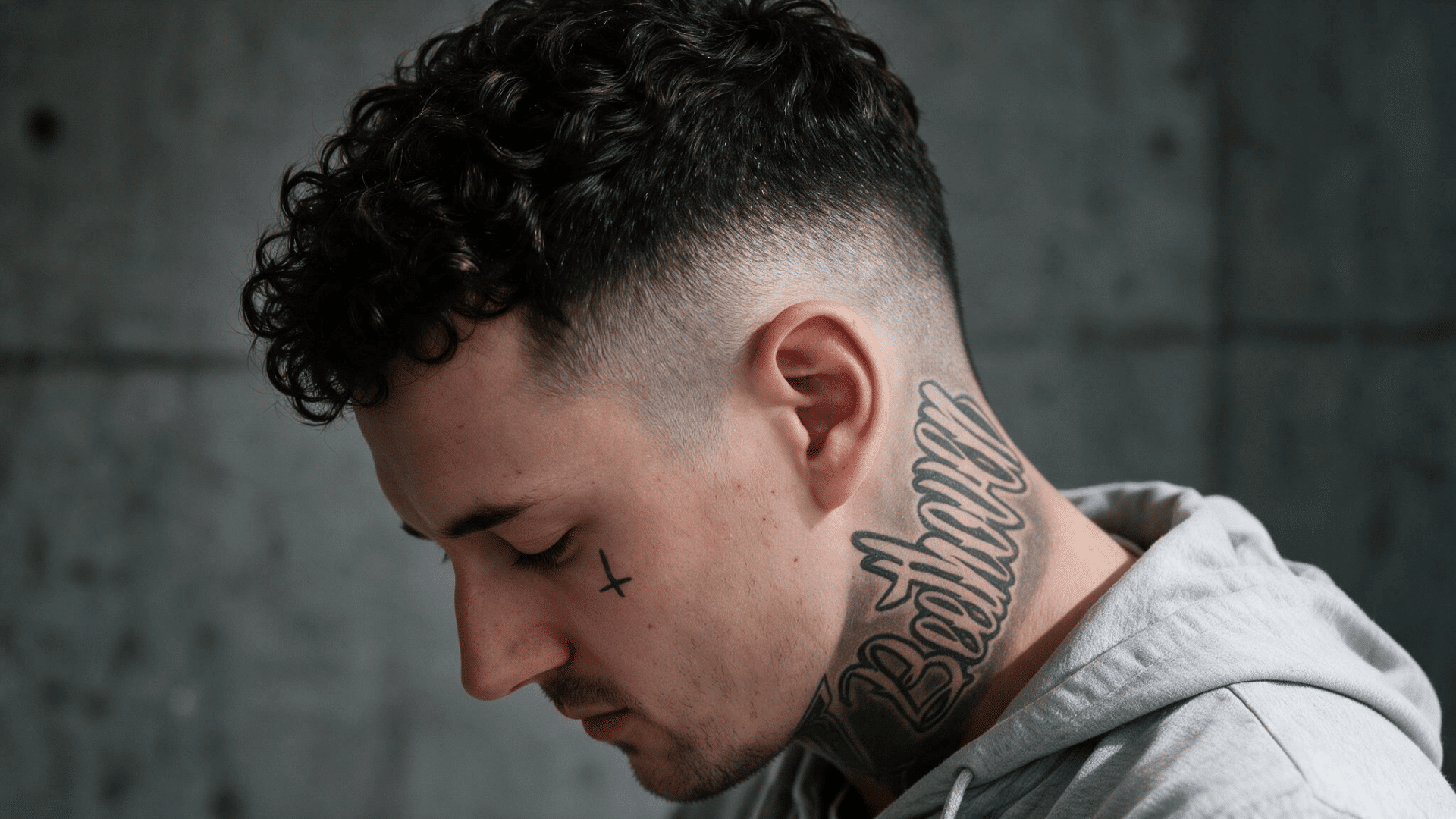 man wearing a curly mohawk with natural dark curls through the center and closely faded hair along both sides of the head