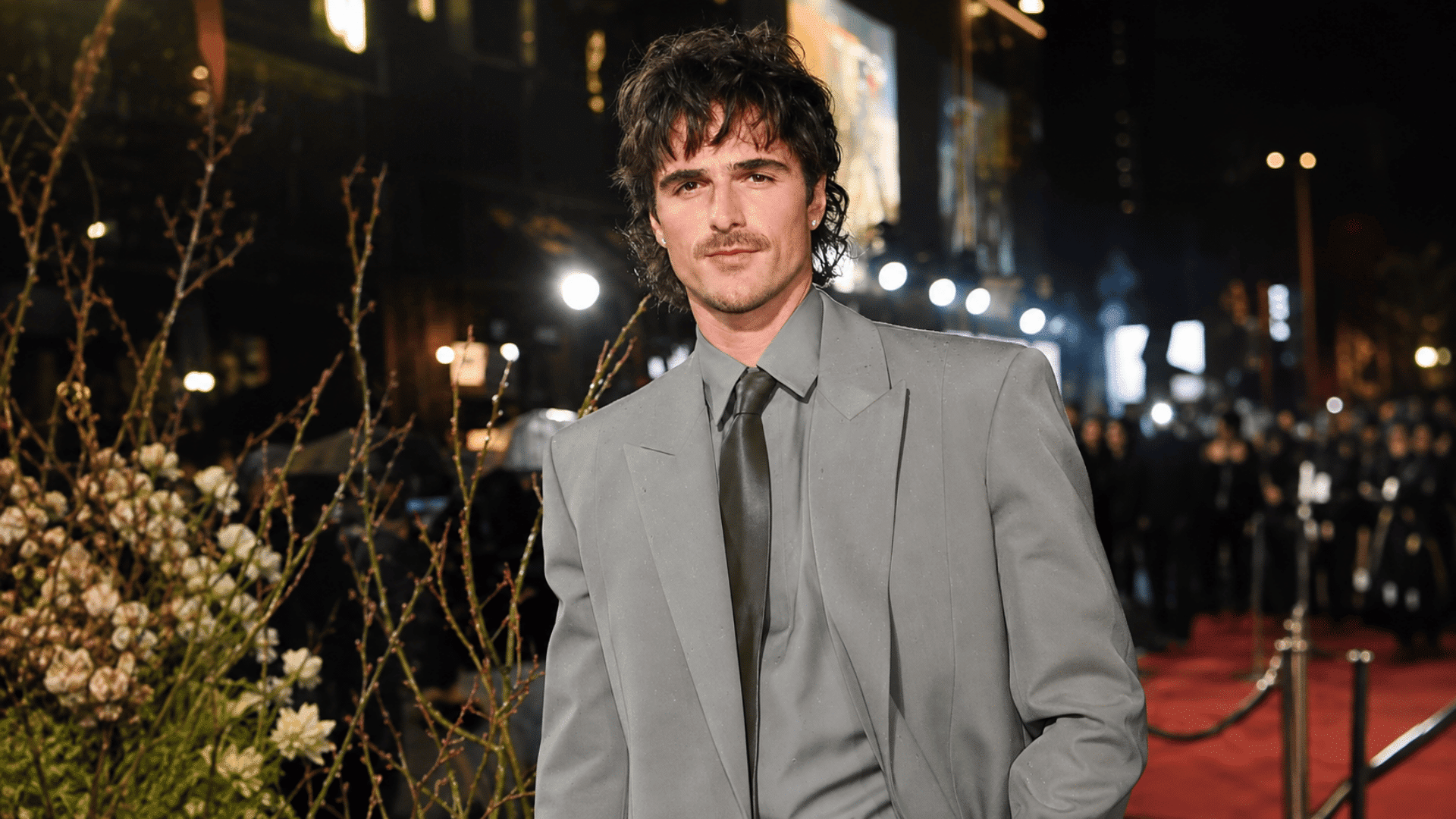 man wearing a low taper haircut with textured dark hair gray suit matching shirt and black tie at a formal event