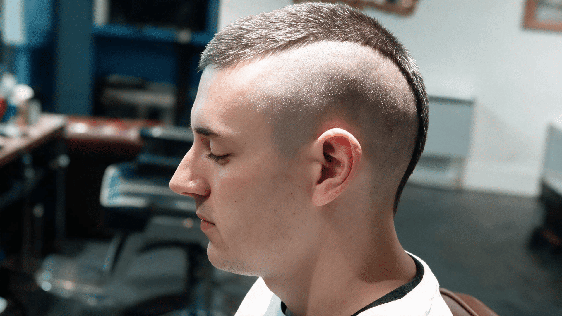 man wearing a mohawk buzz cut with a short center strip and closely shaved hair along both sides and back of the head