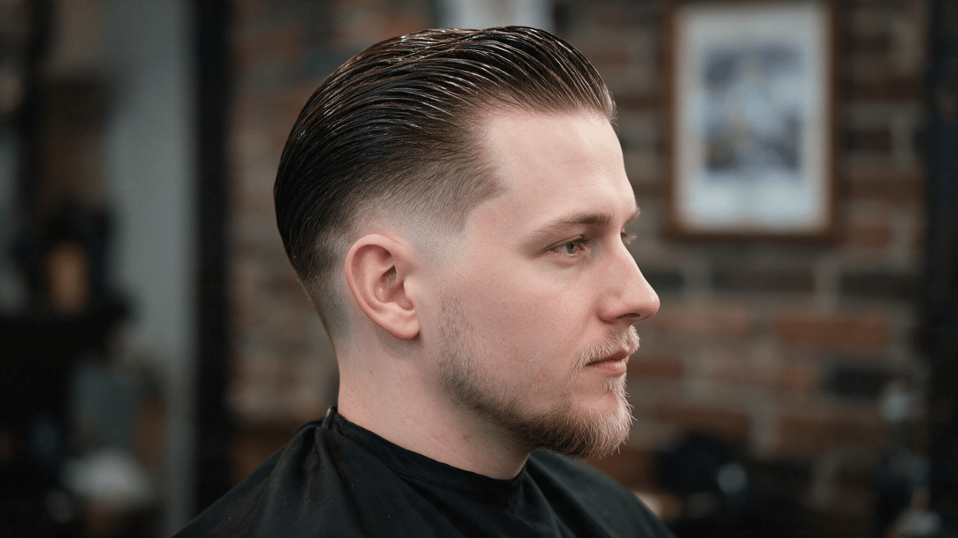 man wearing a slick back mohawk with longer dark hair swept toward the back and closely faded hair along both sides