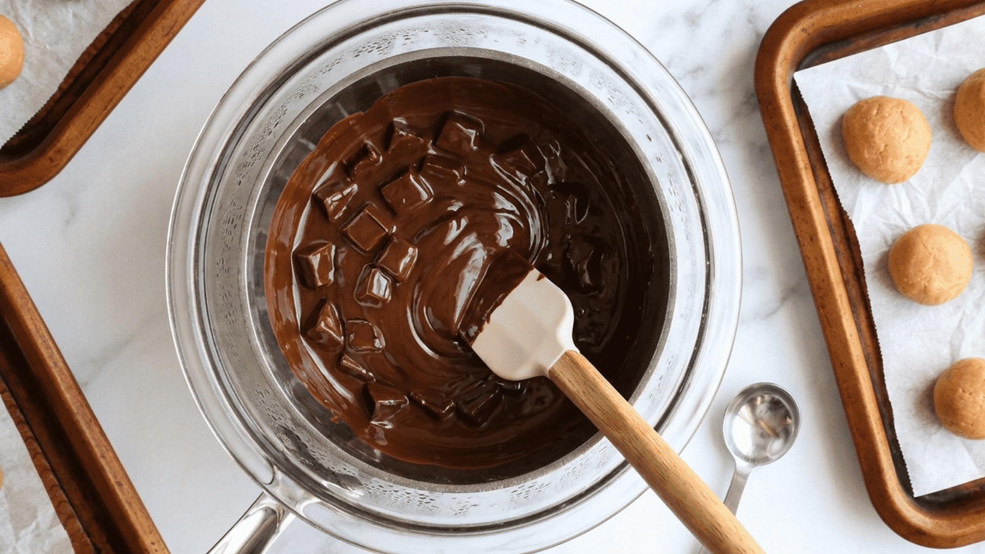 melted chocolate in a glass bowl beside chilled peanut butter balls ready for dipping